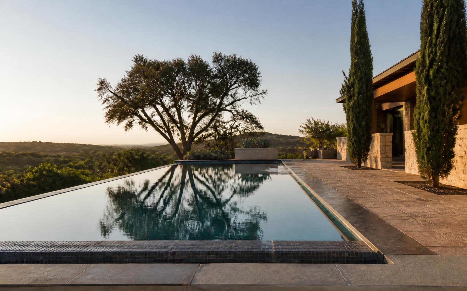 Luxury residential swimming pool with stone coping and glass tile waterline at golden hour