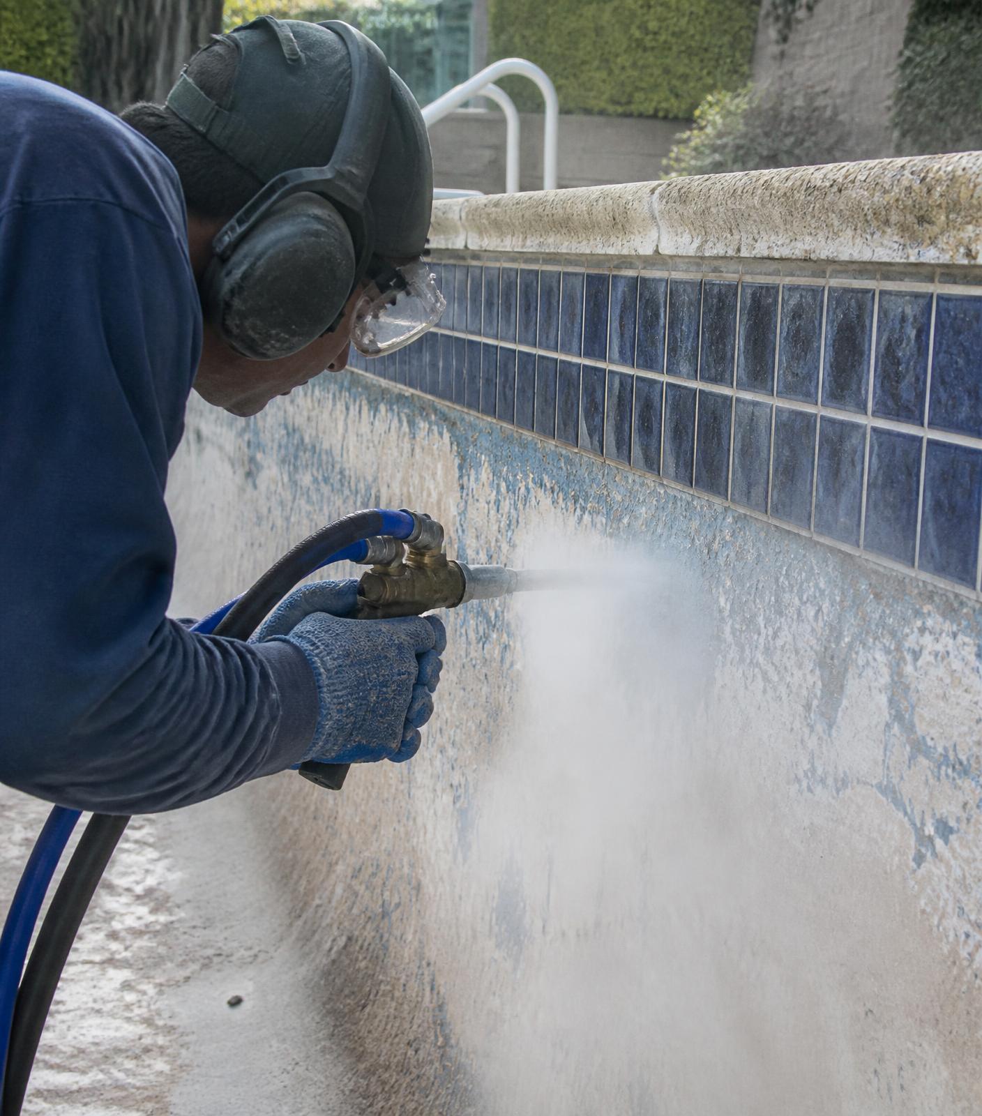 Technician performing professional blasting to remove calcium from pool tile
