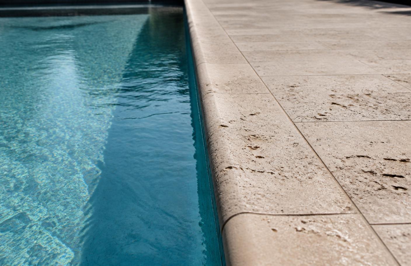 Travertine pool coping beside clear water
